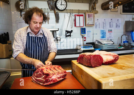 Butcher preparing a large piece of beef in a butcherer's shop. Stock Photo