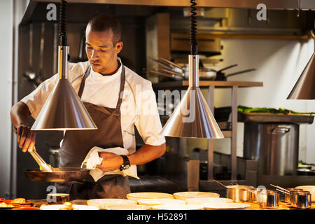 Chef in a restaurant kitchen, plating food. Stock Photo