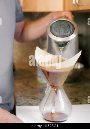 Family preparing breakfast in a kitchen, man making coffee. Stock Photo