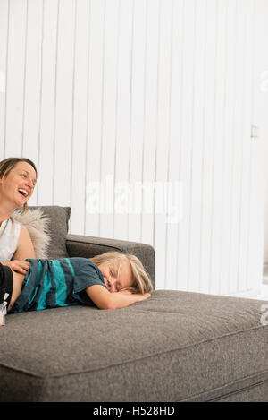 Smiling mother and son lying on a sofa. Stock Photo