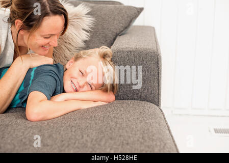 Smiling mother and son lying on a sofa. Stock Photo