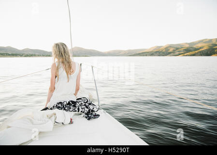 Blond teenage girl sitting on sail boat. Stock Photo