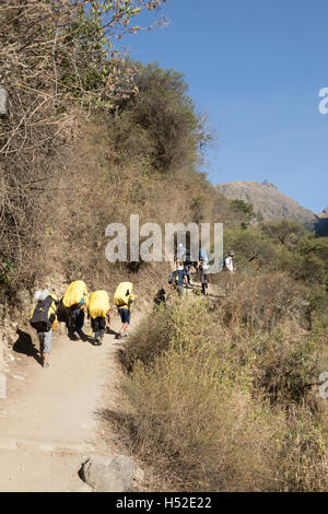 Peruvian porters carrying loads along the Inca Trail towards Dead Woman's Pass in the Sacred Valley of Peru Stock Photo