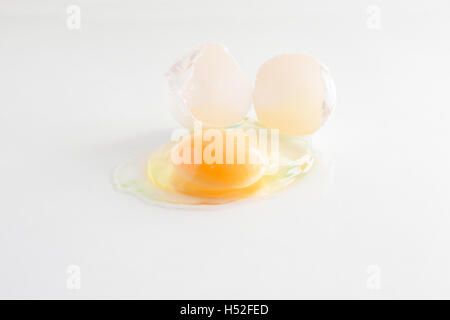 white egg is broken and leaked on a white background. Stock Photo