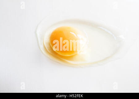 white egg is broken and leaked on a white background.. Stock Photo