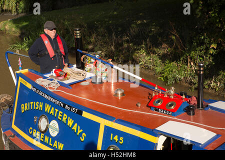 UK, England, Cheshire, Beeston Brook, man steering narrowboat Greenlaw  on Shropshire Union Canal below Beeston Iron Lock Stock Photo