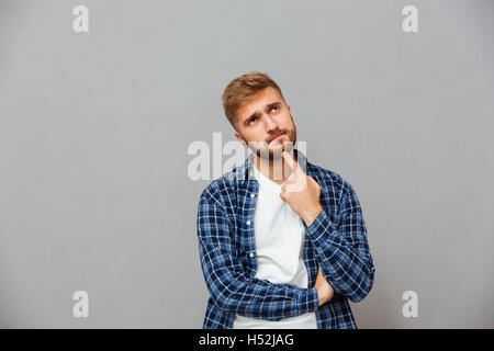 Portrait of a pensive man touching his beard with hand isolated on a gray background Stock Photo