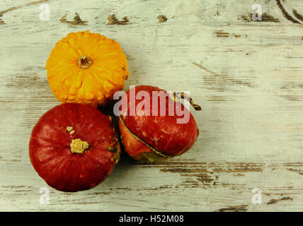 Three decorative pumpkins, two red and one yellow light on the old wooden table with copy space on the right. Top, flat, horizon Stock Photo