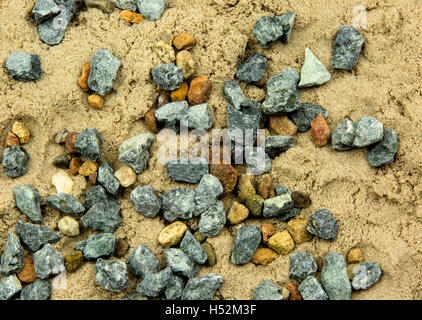Small pebbles scattered on the wet sand, close to the plane view from the top. Interesting natural background and texture.Horizo Stock Photo
