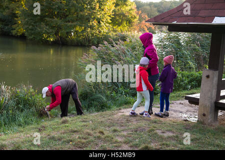 Family of four people on the lake fishing. Caught pike. . Dad fish, little girls are happy. Autumn. Stock Photo