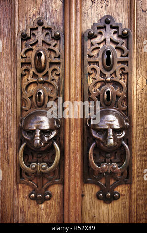 Two door knobs with knocking rings and animal heads in wooden doors Stock Photo