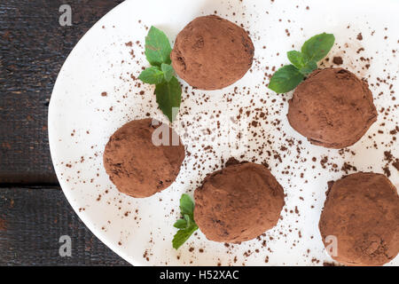 dessert truffles sprinkled with cocoa and mint on a white plate Stock Photo