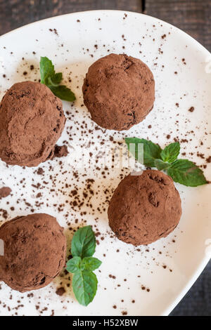 dessert truffles sprinkled with cocoa and mint on a white plate Stock Photo