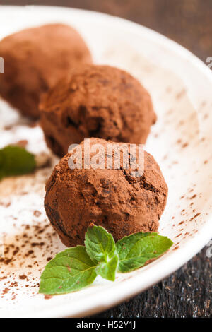 truffles sprinkled with cocoa on a plate with a cup of coffee Stock Photo