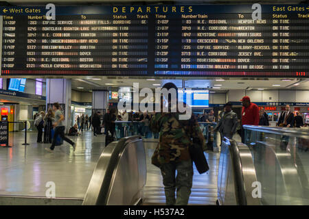 Travelers for Amtrak and NJ Transit in Penn Station in New York on Friday, October 14, 2016 wait by the departure board. Amtrak has started to bring Penn Station into the 21st Century installing digital boards, seen behind older board, in various parts of the station in part to relieve the congestion that occurs around the board. (© Richard B. Levine)