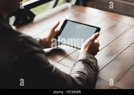 Close-up of young man working on digital tablet while sitting at the cafe Stock Photo
