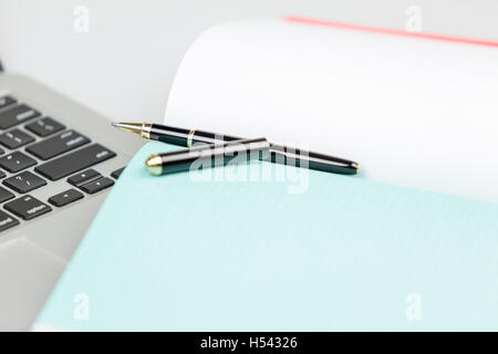 Laptop pc with pen and notebook in foregorund out of focus. pen anc cap in focus. Stock Photo