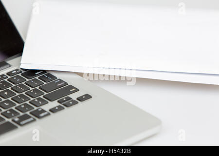 laptop with white paper lying on right hand side of the laptop. focus on the keyboard