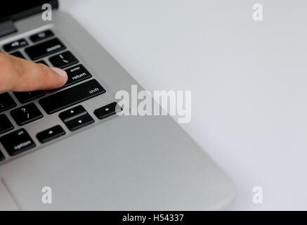 closeup shot with focus on retun key. black keys of a laptop keyboard closeup. a man pressing a return key of a laptop Stock Photo