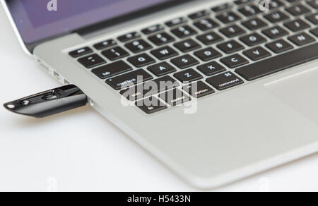 a black usb stick plugged on left side of laptop. closeup shot with focus on keyboard and usb stick Stock Photo