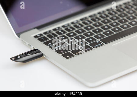a black usb stick plugged on left side of laptop. closeup shot with focus on keyboard and usb stick Stock Photo