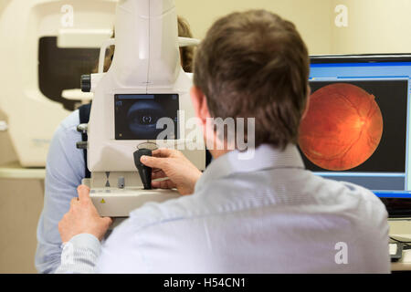 An optician carrying out an eye test using a Optical Coherence Tomography (OCT) machine. Stock Photo