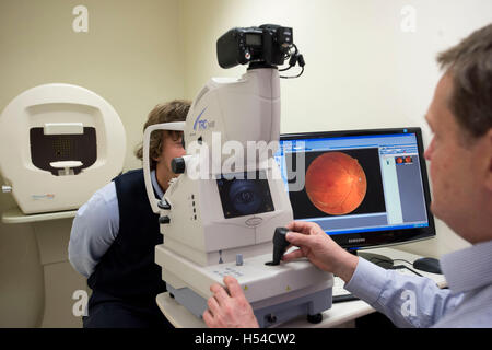 An optician carrying out an eye test using a Optical Coherence Tomography (OCT) machine. Stock Photo