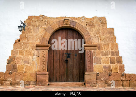 Wooden door on a colonial building with a stone arch in Barichara, Colombia Stock Photo