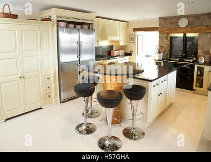 A bespoke country kitchen in a house in the UK using the trunk of a tree as a breakfast island. Stock Photo