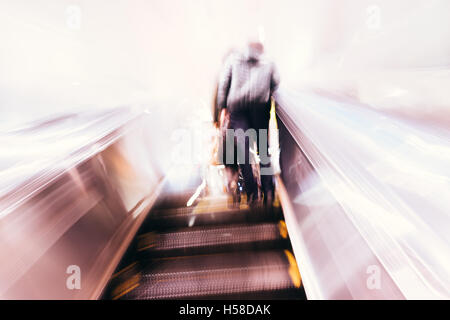 Motion blurred commuters on escalator. Stock Photo