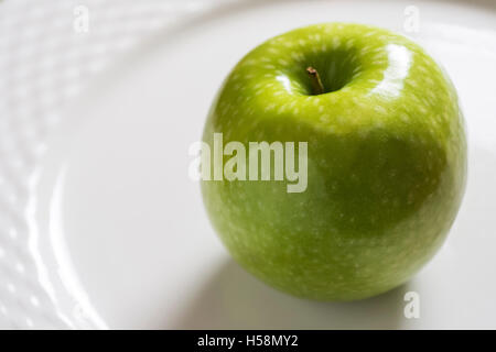 Green Apple on the White Plate. Shiny Organic Granny Smith Close Up. Stock Photo