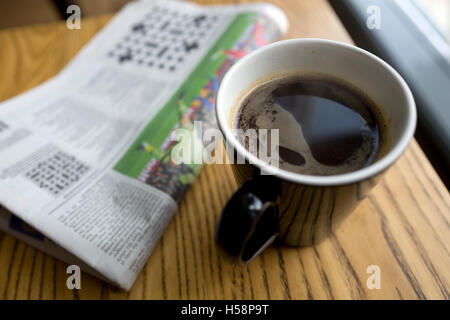 Black coffee and newspaper in cafe, UK Stock Photo