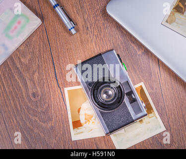 Vintage image with old Camera,old photo,laptop,pen and passport on wood table from above. Stock Photo
