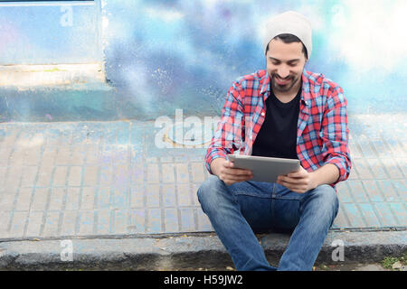 Young latin man touching at tablet at the street. Stock Photo