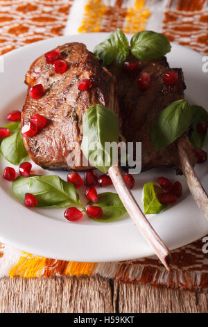 beef steak with pomegranate seeds and basil close-up on a plate. Vertical Stock Photo