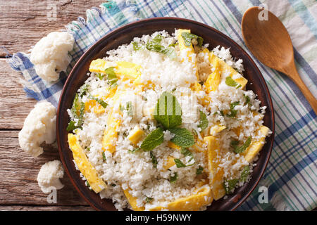 Paleo Food: Cauliflower rice with scrambled eggs and herbs closeup on a plate. horizontal view from above Stock Photo