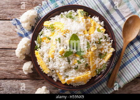 Cauliflower rice with scrambled eggs and herbs closeup on a plate. Horizontal view from above Stock Photo