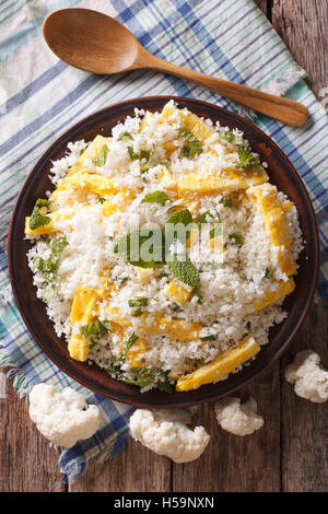 Cauliflower rice with scrambled eggs and herbs closeup on a plate. vertical view from above Stock Photo