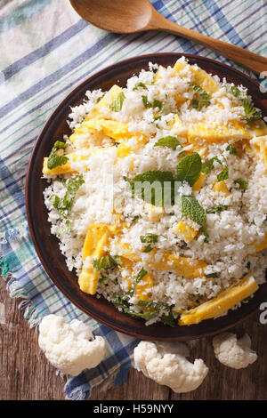 Paleo Food: Cauliflower rice with scrambled eggs and herbs closeup on a plate. vertical view from above Stock Photo