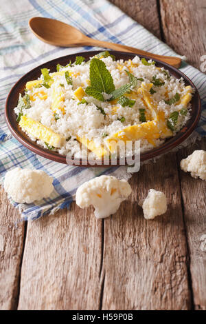 Dietary food: cauliflower rice with scrambled eggs and herbs closeup on a plate. Vertical Stock Photo