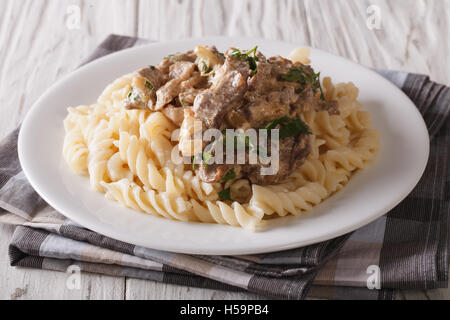 Russian beef stroganoff with pasta fusilli closeup on a plate on the table. horizontal Stock Photo