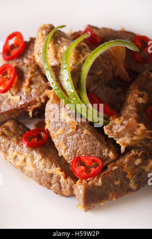 Indonesian cuisine: Beef rendang stewed in coconut milk with spices close-up on a plate. Vertical Stock Photo