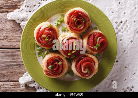 Baked rolls with salami in the form of roses on the table close-up. horizontal top view Stock Photo