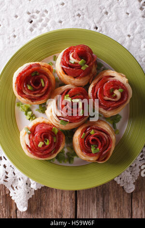 Baked rolls with salami in the form of roses on the table close-up. Vertical top view Stock Photo