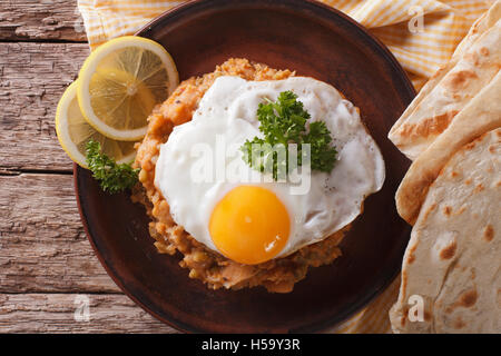 Egyptian breakfast: ful medames with a fried egg and bread close-up on the table. horizontal view from above Stock Photo