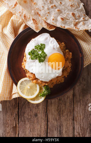 Egyptian breakfast: ful medames with a fried egg and bread on the table. vertical view from above Stock Photo