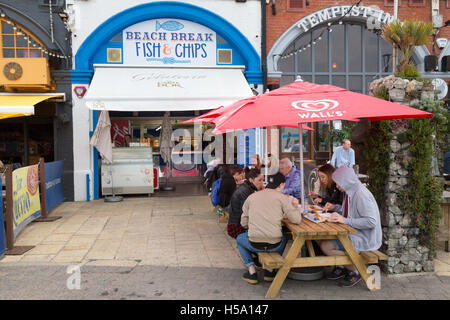 People eating fish & chips outdoors at a seafront cafe, Brighton Promenade, Brighton, East Sussex, England UK Stock Photo