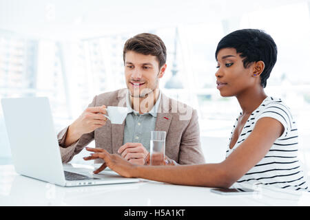 Multiethnic group of young business people having brainstorm in office and working with laptop Stock Photo