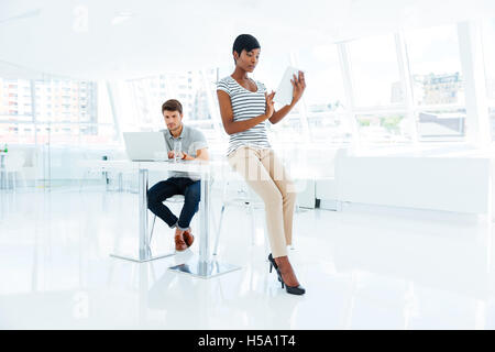 Two young business people working in team in office with laptop and tablet Stock Photo