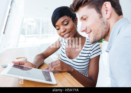 Two young smart happy businesspeople working with tablet in coffee shop Stock Photo